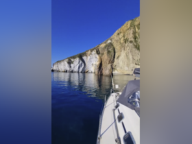 A serene view of a yacht anchored near stunning cliffs, reflecting beautifully in the calm waters — perfect for exploring coastal landscapes.