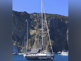 A sleek sailboat docked near stunning rocky cliffs, showcasing the beauty of coastal sailing adventures.