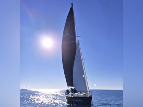 A sleek sailboat glides through shimmering waters under a clear blue sky, showcasing the beauty of sailing adventures.