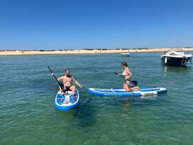 A couple enjoys paddleboarding in clear waters, showcasing a perfect summer day at the beach with fun on the water.