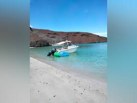 A serene view of a boat docked in crystal-clear turquoise waters, surrounded by rocky cliffs — an ideal setting for a day of exploration and relaxation.