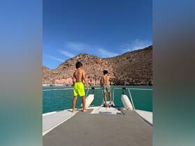 Two boys enjoy the stunning views from the bow of a boat, surrounded by beautiful coastal scenery — a perfect moment for family adventures on the water.