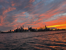 A stunning sunset casts vibrant colors over the Chicago skyline, viewed from the water — a perfect backdrop for evening boat cruises.