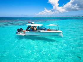 A stylish boat navigates through crystal-clear turquoise waters, showcasing a perfect day for adventure on the sea.