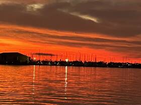 A stunning sunset casts vibrant hues over the harbor, reflecting beautifully on the water — a perfect backdrop for evening boat trips.
