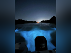 A captivating night view from the back of a boat, showcasing the glowing wake in the water as it moves through the dark, serene surroundings.