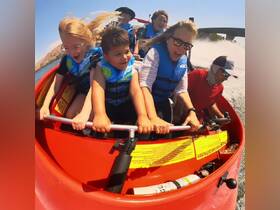 A group of excited guests, including children, enjoy a thrilling jet ski ride, showcasing the fun and adventure of water sports.