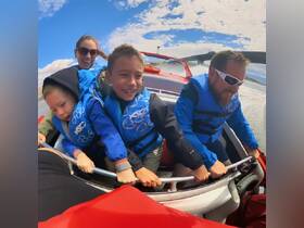 A joyful family enjoys a thrilling ride on a speedboat, with kids wearing life jackets and smiles all around — perfect for family adventures on the water.