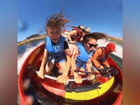 A group of excited riders enjoy a thrilling jet boat experience, capturing the joy and adrenaline of water sports on a sunny day.