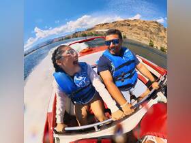 A joyful moment captured on a speedboat, showcasing a girl and a man enjoying their ride on the water, filled with laughter and excitement.