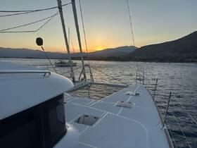 A serene sunset view from the deck of a catamaran, showcasing the tranquil waters and distant mountains — perfect for a peaceful evening on the water.