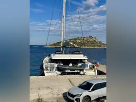 A beautiful yacht docked at a serene location, showcasing its sleek design against a backdrop of clear blue waters and a rocky island.