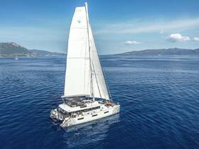 A stunning aerial view of a catamaran sailing through calm blue waters, showcasing its sleek design and spacious deck — perfect for luxury charters and island adventures.