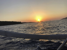 A stunning sunset view over the water, with a distant sailboat and a serene coastline, perfect for capturing the beauty of a day on the water.