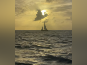 A serene sunset view of a sailboat gracefully navigating the open waters, creating a picturesque scene perfect for sailing enthusiasts.