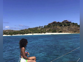 A woman enjoys the stunning view of a tropical island from the deck of a boat, capturing the essence of relaxation and adventure on the water.