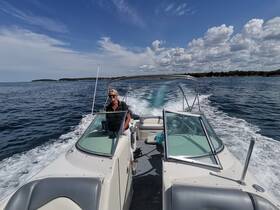 A woman confidently navigates a boat through serene waters, showcasing the beauty of a day on the ocean.