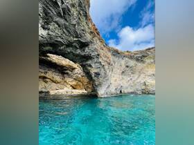 A stunning view of a rocky coastline and cave, with crystal-clear turquoise waters — a perfect representation of the natural beauty found on boating adventures.