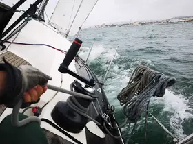 A close-up view of the helm on a sailing boat, showcasing the winch and ropes in action as the vessel navigates through the waves.