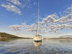 A serene view of a sailboat gliding through calm waters under a beautiful sky, perfect for showcasing peaceful sailing experiences.