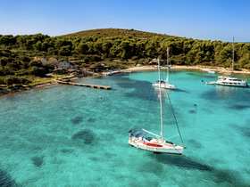 A stunning aerial view of sailboats anchored in crystal-clear turquoise waters, surrounded by lush greenery — a perfect setting for a serene getaway.