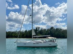 A sleek sailboat navigates through turquoise waters, showcasing a perfect day for sailing adventures amidst a picturesque backdrop.