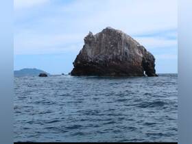 A stunning view of a unique rock formation rising from the ocean, showcasing the natural beauty of the coastline — perfect for sightseeing and photography during boat tours.
