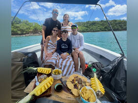 A joyful family enjoys a delicious spread of snacks aboard a boat, surrounded by stunning coastal scenery — perfect for memorable family outings.