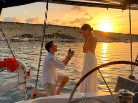 A romantic sunset proposal aboard a yacht, capturing a couple's special moment against a stunning backdrop of golden skies and calm waters.