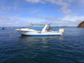A fishing boat named 'La Huida' is seen on the water, with a person actively fishing, showcasing a serene day on the ocean.