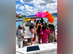 A vibrant group celebrates aboard a boat, adorned with colorful balloons, creating a festive atmosphere perfect for parties and gatherings on the water.