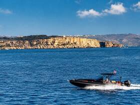 A speedboat glides through the sparkling blue waters, showcasing a stunning coastal backdrop — perfect for adventure seekers exploring the coastline.