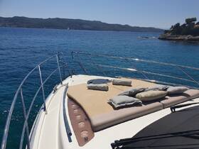 A serene view of the bow of a yacht, featuring comfortable cushions on the sun deck, perfect for relaxing while cruising through clear blue waters.