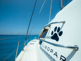 A sleek Leopard catamaran glides through crystal-clear waters, showcasing its elegant design and branding — perfect for luxury sailing adventures.