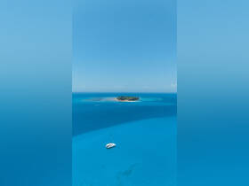 A stunning aerial view of a catamaran sailing in vibrant turquoise waters, with a picturesque island in the background, perfect for showcasing tropical sailing adventures.