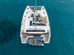 Aerial view of a sleek catamaran anchored in crystal-clear waters, showcasing its modern design and solar panels — perfect for eco-friendly sailing adventures.