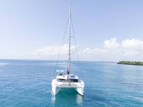 A stunning view of a catamaran sailing through crystal-clear waters, showcasing its sleek design against a picturesque backdrop.