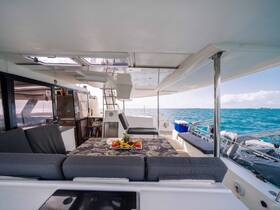 A spacious and inviting lounge area inside a yacht, featuring comfortable seating and a beautifully arranged table with fresh fruits, perfect for relaxing while enjoying the ocean views.