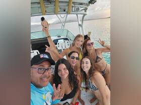 A lively group of friends enjoys a fun day on the boat, capturing joyful moments and celebrating together in the beautiful waters.
