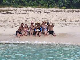 A cheerful group enjoys a beach day at a sandbar, relaxing and celebrating together in the sun — perfect for memorable outings on the water.
