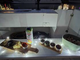 A beautifully arranged spread of snacks and drinks on a boat, featuring cheese, olives, and a refreshing beverage — perfect for a relaxing evening on the water.