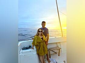 A couple enjoys a picturesque sunset on a boat, capturing a moment of joy and romance on the water.