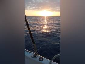 A serene sunset view from the deck of a boat, showcasing the tranquil ocean waters reflecting the golden hues of the setting sun.