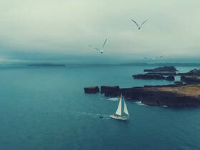 A serene sailing scene featuring a boat navigating through calm waters, surrounded by rocky islands and seagulls in flight — a picturesque moment perfect for nature lovers.
