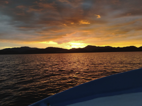 A stunning sunset view from the deck of a boat, showcasing vibrant colors reflecting on the water — perfect for serene evening cruises.