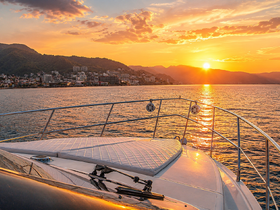 A stunning sunset view from the deck of a yacht, showcasing the serene waters and distant city skyline — perfect for romantic evening cruises.