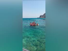 A lively group enjoys a refreshing swim in crystal-clear waters, celebrating together in a picturesque beach setting.