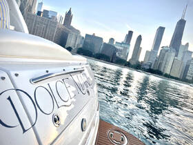 A close-up view of the 'Dolce Mare' yacht with a stunning city skyline in the background, showcasing the perfect blend of luxury and urban scenery on the water.