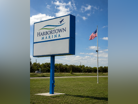 The Harbortown Marina sign stands prominently against a clear blue sky, indicating a welcoming destination for boaters and visitors.
