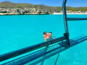 A joyful moment captured as a father and child enjoy swimming in the crystal-clear waters, showcasing the perfect family adventure on the beach.